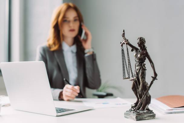 stock photo themis figurine table blurred lawyer talking mobile phone background